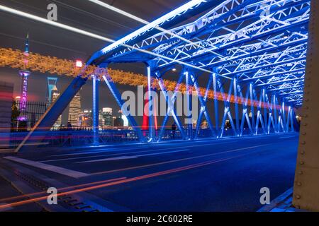 Nachtansicht der Waibaidu Bridge, einer der Wahrzeichen von Shanghai, mit Verkehr und modernen Wolkenkratzern im Hintergrund. Stockfoto