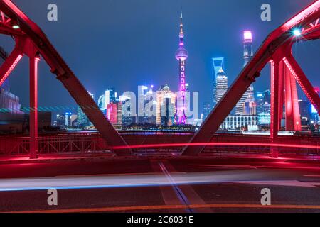Nachtansicht der Waibaidu Bridge, einer der Wahrzeichen von Shanghai, mit Verkehr und modernen Wolkenkratzern im Hintergrund. Stockfoto