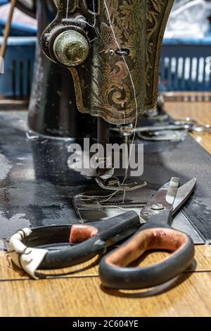 Die alte Schneiderschere liegt an der veralteten Nähmaschine, Nahaufnahme. Stockfoto