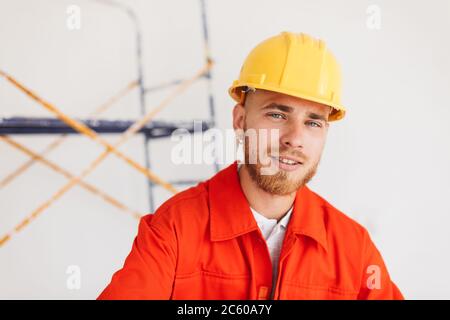 Portrait des jungen Baumeisters in orange Arbeitskleidung und gelb hart Stockfoto