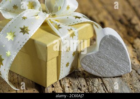 Weihnachtsgeschenk mit goldener Stern-Schleife und Herzform auf Holz Hintergrund, close-up Stockfoto