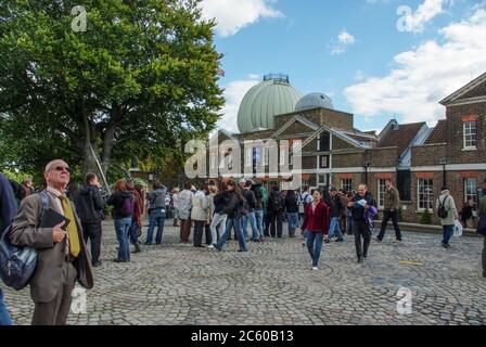 Royal Observatory, Greenwich, London, Großbritannien; Besucher stehen in einer Schlange, um auf der Meridian-Linie zu stehen. Stockfoto