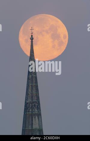 Salisbury, Wiltshire, Großbritannien. Mai 2020. Der Flower Supermoon hängt tief am frühen Morgenhimmel über der Salisbury Cathedral, die ihre 800 feiert Stockfoto