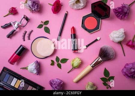 Make-up Produkte und Ausrüstung mit Blumen auf rosa Hintergrund. Draufsicht Stockfoto