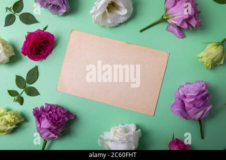 Leere Grußkarte auf grünem Hintergrund mit Blumenrahmen. Draufsicht Stockfoto