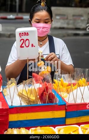 Straßenverkäufer trägt Gesichtsmaske während covid 19 Pandemie, Bangkok, Thailand Stockfoto