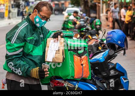 Grab Motorrad Lieferung Fahrer trägt Gesichtsmaske während covid 19 Pandemie, Bangkok, Thailand Stockfoto