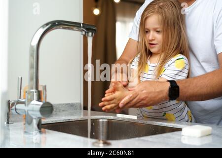 Vater und Tochter waschen sich die Hände über dem Waschbecken in einer Küche Stockfoto