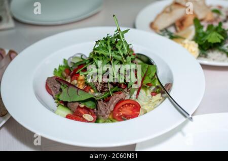 Salat mit kastanischem Rinderkirsche auf einem weißen Teller Stockfoto