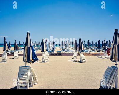 Sonnenschirme und Liegestühle an einem sonnigen und einsamen Strand geschlossen Stockfoto