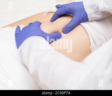 Der Arzt untersucht den Magen eines Mädchens auf das Vorhandensein von Nabelbruch. Bauchwandkrankheit Konzept mit Nabelbruch Stockfoto