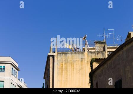 Einige Antennen und eine Satellitenschüssel auf dem Dach eines Hauses in der Nähe von Kleidung, die an einem Draht hängt (Pesaro, Italien, Europa) Stockfoto