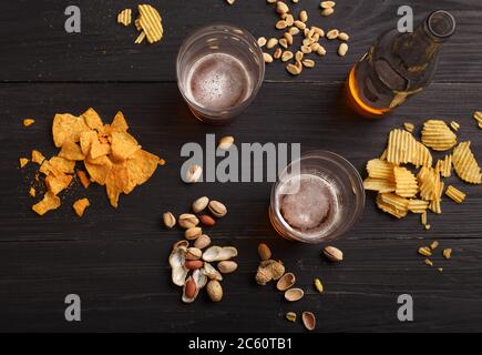 Lager und Snack. Bier in Flaschen und Gläsern, Chips, Nüssen und Pistazien Stockfoto