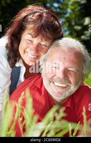 Zwei lachende Senioren liegen glücklich im Gras Stockfoto