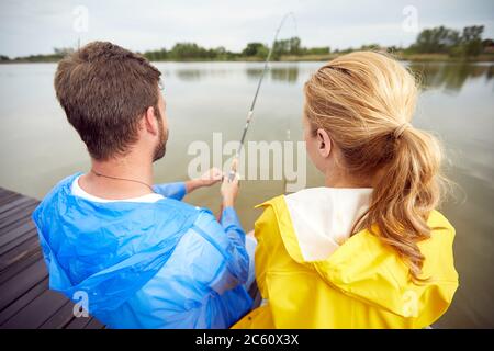 Junges Paar genießen auf Teich und Angeln zusammen.Rückansicht Stockfoto
