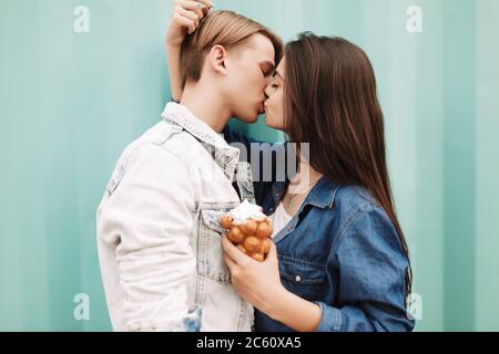 Portrait von jungen schönen Paar umarmen und küssen sich gegenseitig, während auf blauem Hintergrund stehen Stockfoto