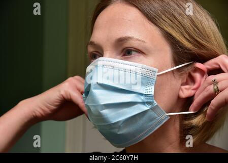 FRSM oder Fluid Surgical Mask wird von einem NHS-Mitarbeiter im Kampf gegen Covid-19 modelliert. Eine dreilagige Maske oder OP-Maske, die richtige Art zu tragen. Stockfoto