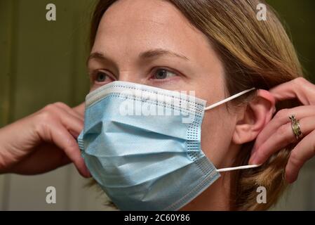 FRSM oder Fluid Surgical Mask wird von einem NHS-Mitarbeiter im Kampf gegen Covid-19 modelliert. Eine dreilagige Maske oder OP-Maske, die richtige Art zu tragen. Stockfoto