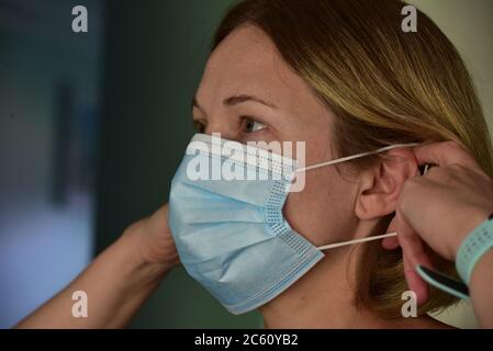 FRSM oder Fluid Surgical Mask wird von einem NHS-Mitarbeiter im Kampf gegen Covid-19 modelliert. Eine dreilagige Maske oder OP-Maske, die richtige Art zu tragen. Stockfoto