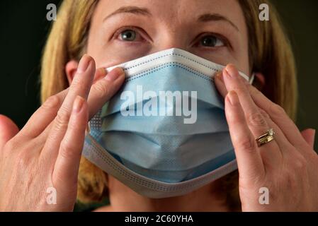 FRSM oder Fluid Surgical Mask wird von einem NHS-Mitarbeiter im Kampf gegen Covid-19 modelliert. Eine dreilagige Maske oder OP-Maske, die richtige Art zu tragen. Stockfoto