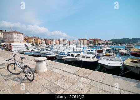 Das Fahrrad ist auf dem Pier im Hafen von Rovinj, Kroatien geparkt. Yachten Landung, Motorboote und Boote auf dem Wasser, mittelalterliche Vintage-Häuser der Altstadt auf der b Stockfoto