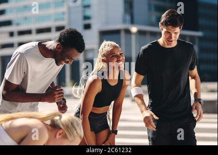 Multiethnische Freunde in der Stadt nach dem Workout. Fitnessgruppe, die sich nach dem Workout ausruhen und lächeln lässt. Stockfoto