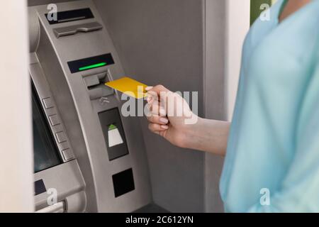 Nicht erkennbare Frau, die Gold-Kreditkarte in Geldautomaten im Freien, um Bargeld zu nehmen Stockfoto