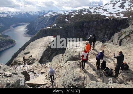 TROLLTUNGA, NORWEGEN - 16. JULI 2015: Menschen warten in der Schlange, um Fotos am Trolltongue (Trolltunga)-Kanzelfelsen im Landkreis Hordaland, Norwegen, zu machen. Die 22k Stockfoto