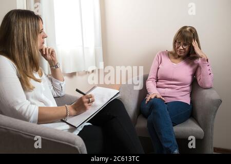 Psychologe in seinem Büro, der einen Patienten betreut und Notiz nimmt. Stockfoto