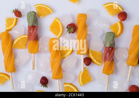 Orange Sorbet mit Eis, Scheiben von Orange und Erdbeeren auf weißem Hintergrund. Draufsicht flach Lay Sommer Konzept Stockfoto