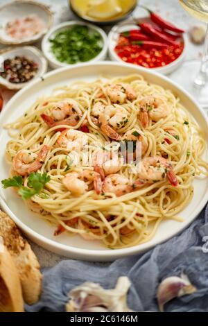 Spaghetti mit Garnelen auf weißem Keramikplatte und serviert mit einem Glas Weißwein Stockfoto