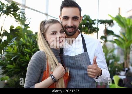 Glückliche junge Kollegen stehen bei Pflanzen im Gewächshaus Stockfoto