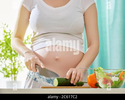Eine schwangere Frau bereitet Salat Stockfoto