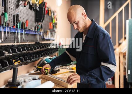 Junger Vorarbeiter in Arbeitskleidung mit Maßband Zeit verbringen Stockfoto