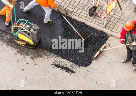 Asphalt Pflaster Arbeiter manuelle Maschine, Arbeiter Ebene die Asphaltschicht vor dem Einschlagen Blick von oben Stockfoto