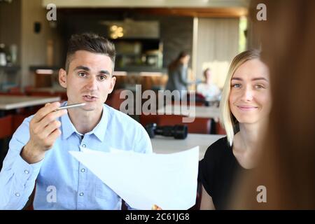 Lächelnde Menschen diskutieren im Café über Arbeitsfragen Stockfoto