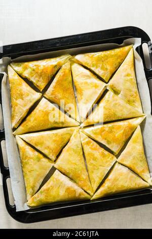 indische Samosa aus Phyllo mit würzigen Kartoffeln und Gemüse auf einem Backblech, fertig zum Backen im Ofen mit schwarzen Sesamsamen Stockfoto