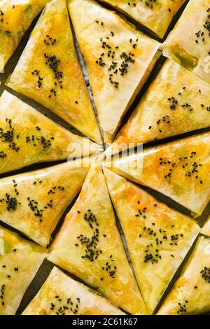indische Samosa aus Phyllo mit würzigen Kartoffeln und Gemüse auf einem Backblech, fertig zum Backen im Ofen mit schwarzen Sesamsamen Stockfoto