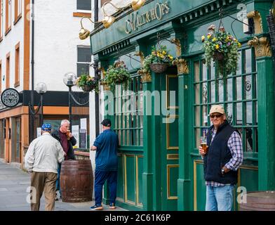 Leith, Edinburgh, Schottland, Großbritannien, 6. Juli 2020. Cafe Kultur & Pub Eröffnung beginnt: Cafés und Pubs entlang der Küste beginnen, Straßenpflaster für Mahlzeiten und Getränke bieten und die Gegend fühlt sich viel geschäftiger als in den letzten Monaten. Pub Biergärten und Außenbereiche können ab heute in Schottland geöffnet. Männer genießen ein Bier vor dem traditionellen Pub Malt & Hops Stockfoto