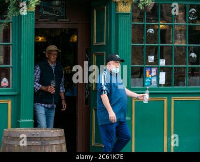 Leith, Edinburgh, Schottland, Großbritannien, 6. Juli 2020. Cafe Kultur & Pub Eröffnung beginnt: Cafés und Pubs entlang der Küste beginnen, Straßenpflaster für Mahlzeiten und Getränke bieten und die Gegend fühlt sich viel geschäftiger als in den letzten Monaten. Pub Biergärten und Außenbereiche können ab heute in Schottland geöffnet. Männer genießen ein Bier vor dem traditionellen Pub Malt & Hops Stockfoto