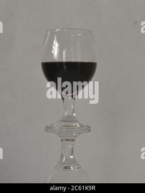 Glas oder Kristallglas Tassen, in der Regel konsumiert, um Wein oder andere traditionelle Getränke zu trinken, in Reflexion mit weißem Hintergrund Stockfoto