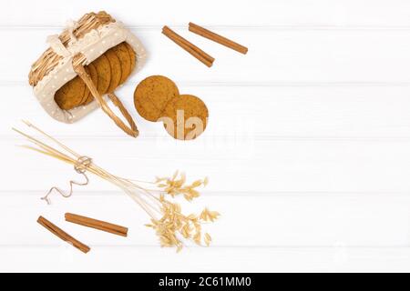 Haferflocken mit Haferstämmen Ohren und Zimtstangen auf weißem Holztisch. Draufsicht, flach liegend. Essen Herbst Hintergrund im rustikalen Stil Stockfoto