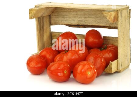 Ein Bündel frischer und farbenfroher italienischer Pflaumentomaten in einer Holzkiste auf weißem Hintergrund Stockfoto