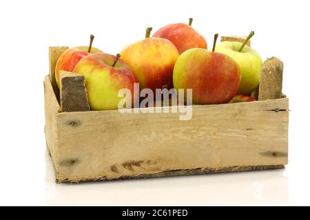 Frische rote und gelbe Äpfel aus einer Holzkiste auf weißem Grund Stockfoto