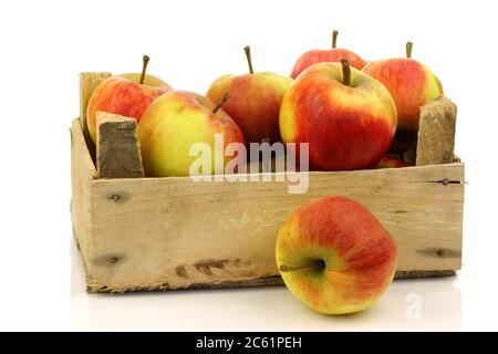 Frische rote und gelbe Äpfel aus einer Holzkiste auf weißem Grund Stockfoto