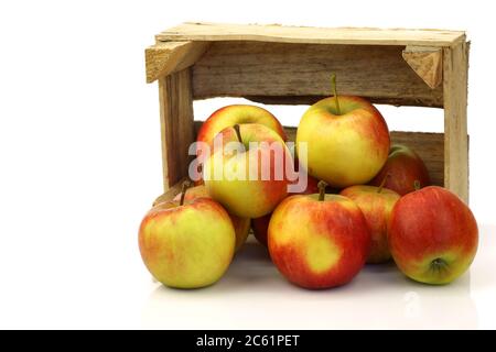 Frische rote und gelbe Äpfel aus einer Holzkiste auf weißem Grund Stockfoto