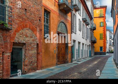 Enge gepflasterte Straße entlang bunten Häusern in der Altstadt von Alba, Piemont, Norditalien. Stockfoto