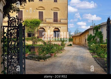 Ein Blick in den Innenhof über das offene Tor von eisernen Zaun eines alten mittelalterlichen Bauernhaus. Toskana, Italien Stockfoto