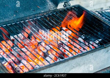 Heißer leerer tragbarer Barbecue Grill mit flammendem Feuer und Kohle auf schwarzem Hintergrund. Warten auf die Platzierung Ihrer Lebensmittel. Nahaufnahme Stockfoto
