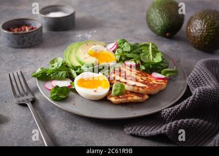 Gesunde keto paleo Diät Frühstück: gekochtes Ei, Avocado, Halloumi Käse, Salat Stockfoto